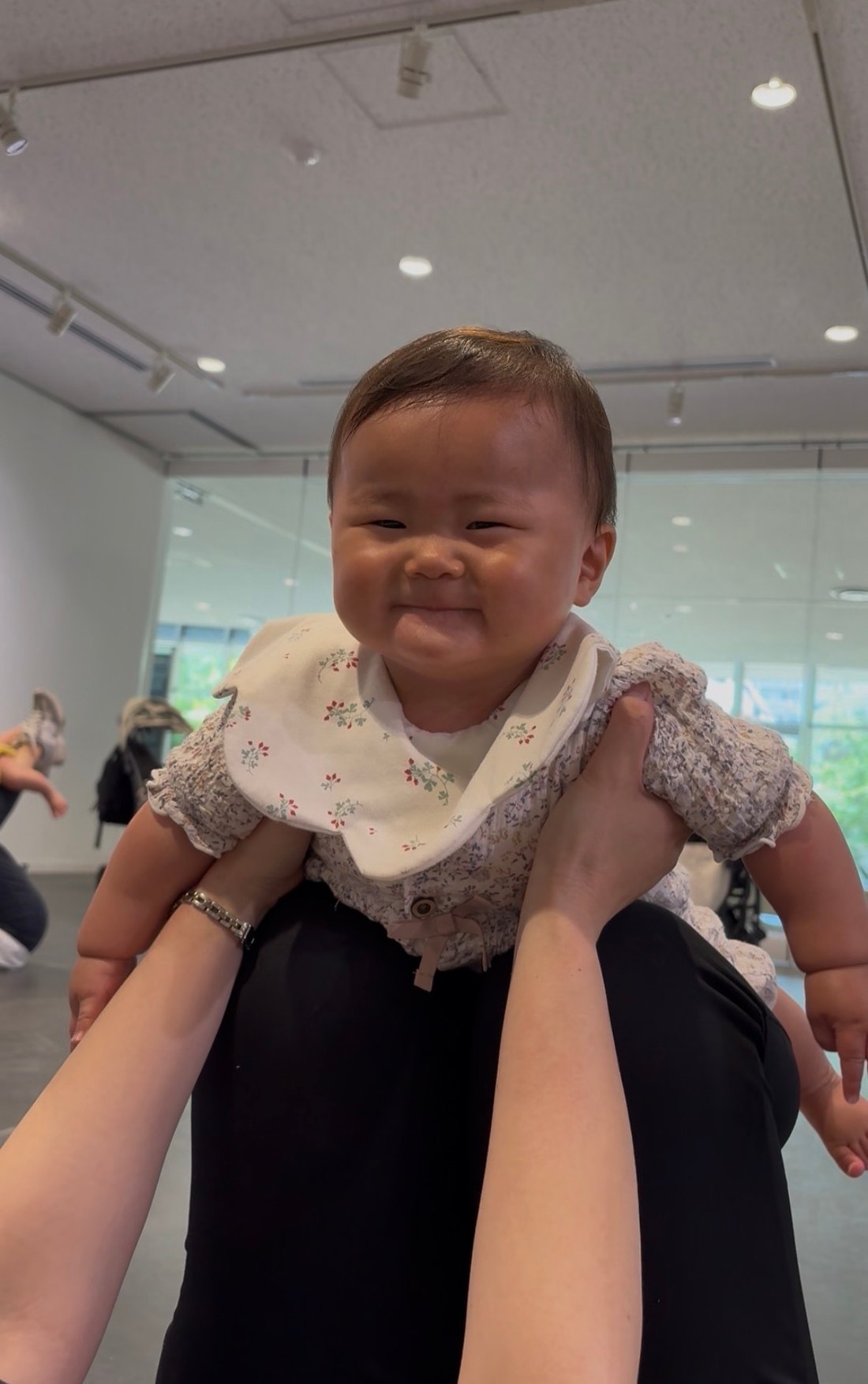 ママに高く抱き上げられて笑う赤ちゃん
