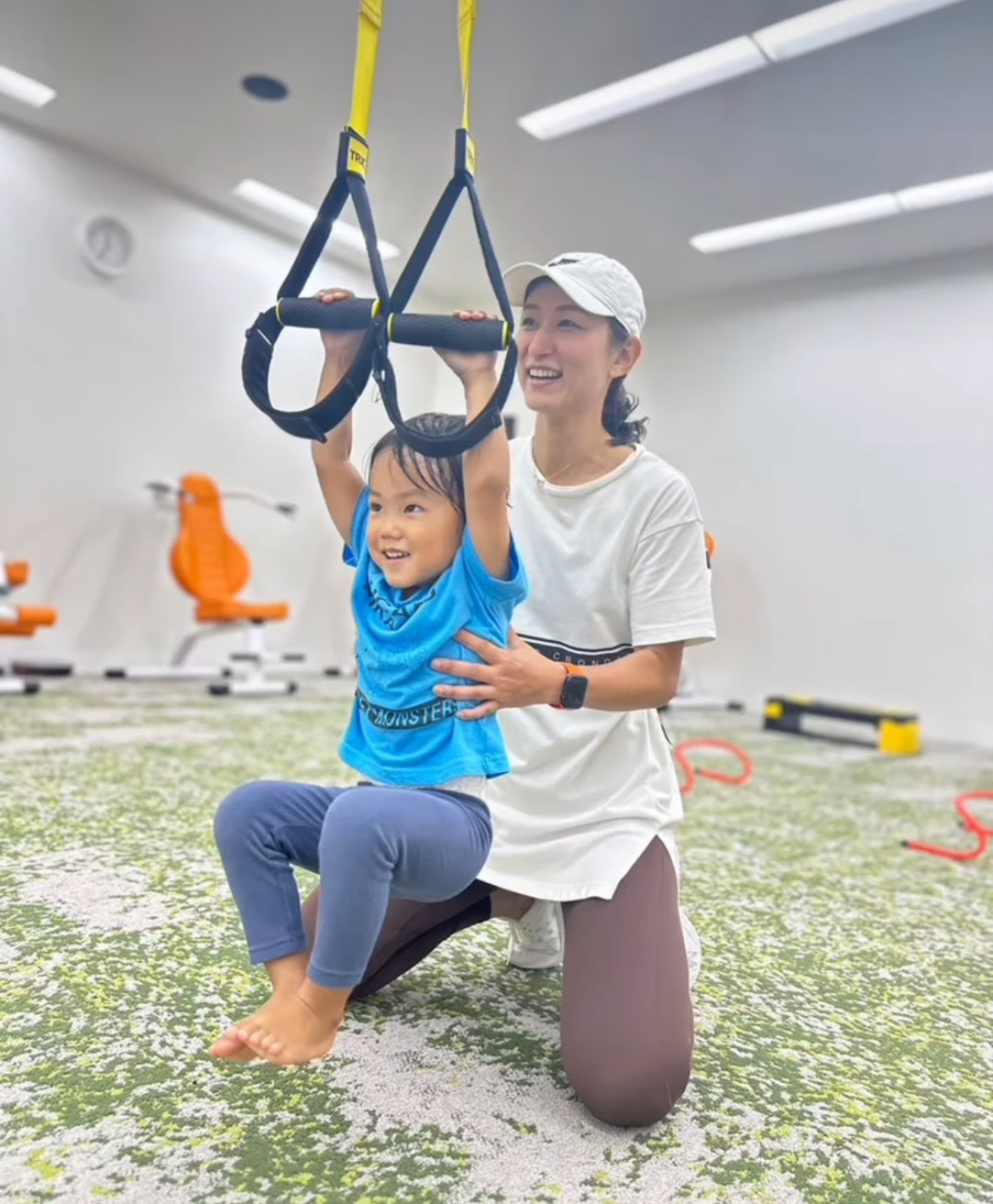 日曜の親子体操でTRXにつかまる子どもを支えるトレーナー
