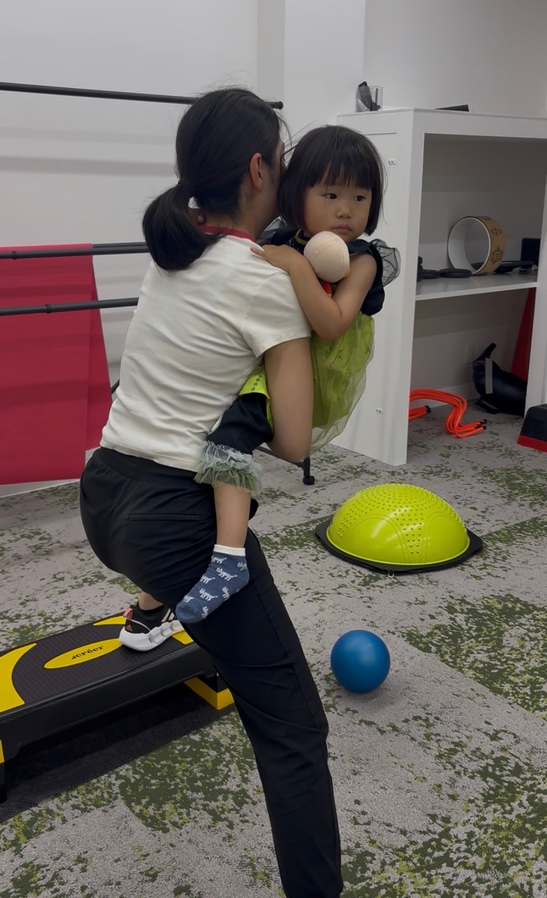 子どもを背中に乗せてステップ台を上がるママ